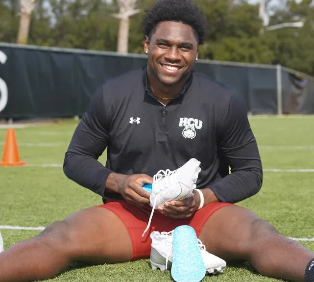 Jalyx Hunt holding Blumaka NonSlip insoles and his cleats