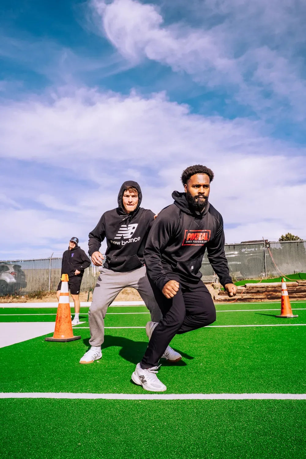 Two athletes driving out of a lateral start on turf during a speed session, wearing Blumaka NonSlip