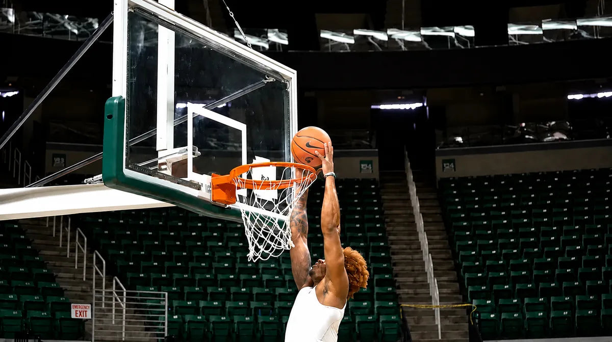 Basketball player rising for a dunk in an empty arena