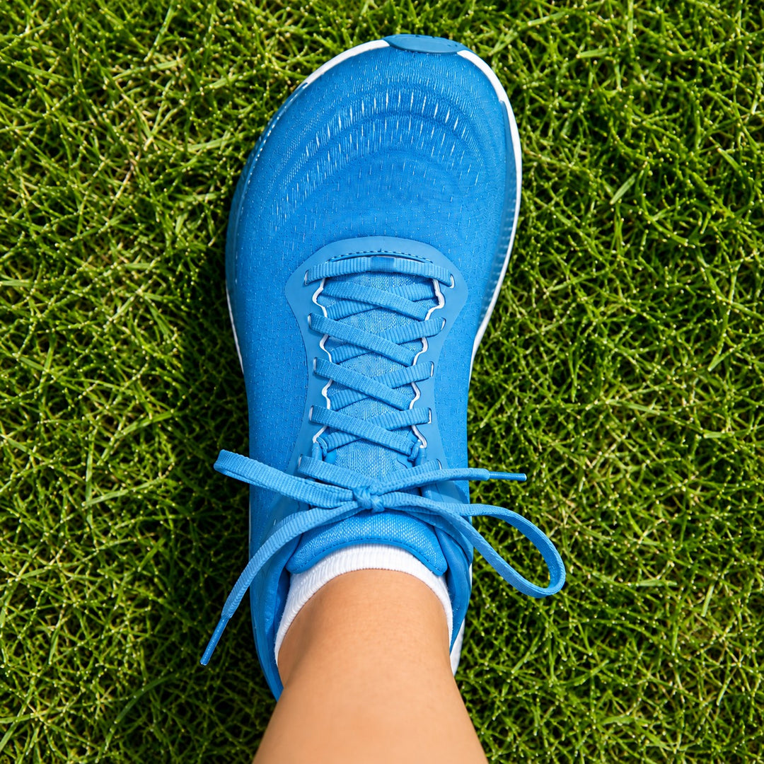 Top-down view of a runner's wide toe box shoe on grass